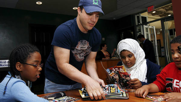 IMAGE DISTRIBUTED FOR DC COMICS -GREEN LANTERN #0 writer and DC Entertainment Chief Creative Officer Geoff Johns hands out comic books to Zwena Gray, 10, of Detroit, from left, Layla Burson-Benthar, 11, and Jamil Burson-Benthar, 8, of Detroit during a sup