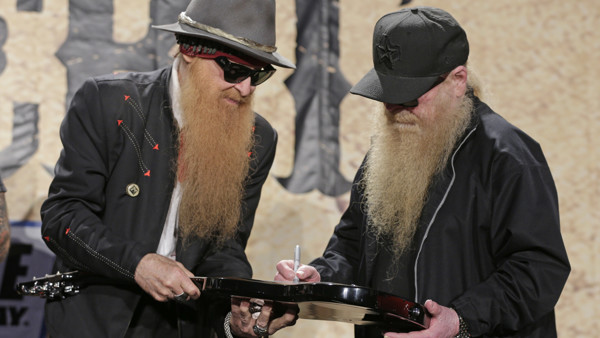 ZZ Top members Billy Gibbons, left, and Dusty Hill, right, autograph a guitar for Speedway Children's Charities during a news conference at Charlotte Motor Speedway in Concord, N.C., Tuesday, April 7, 2015. ZZ Top will play a concert before the NASCAR Coc
