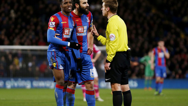 Crystal Palace's Wilfried Zaha (left) is spoken to by referee Mike Jones after being booked for dissent as Mile Jedinak looks on during the Barclays Premier League match at Selhurst Park, London.