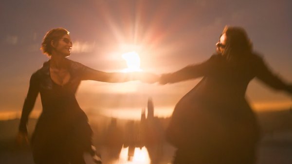 Trinity and Neo touching hands in the sky.